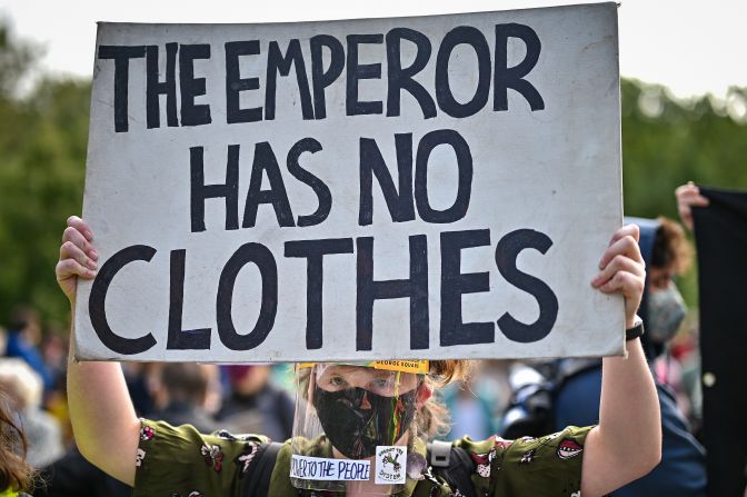 Un joven sostiene un cartel que dice "El emperador no tiene ropas" durante la protesta por el clima frente al Parlamento escocés, en Glasgow.