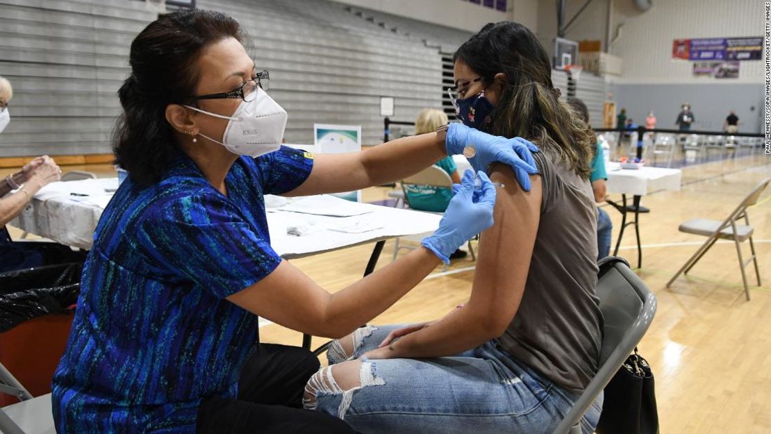 a enfermera Susanna Bryan administra una dosis de la vacuna COVID-19 de Pfizer a Joann Cortes en una clínica de vacunación en la escuela secundaria de Winter Springs