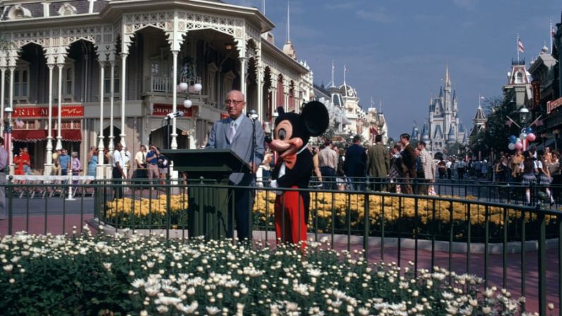Roy O. Disney, hermano de Walt Disney, se une a Mickey Mouse en la ceremonia de inauguración en 1971. Walt Disney había fallecido en 1966. "Que Walt Disney World traiga alegría e inspiración y nuevos conocimientos a todos los que vengan a este feliz lugar... un Reino Mágico donde los jóvenes de corazón de todas las edades puedan reír, jugar y aprender juntos", dijo Roy. Créditos: Disney
