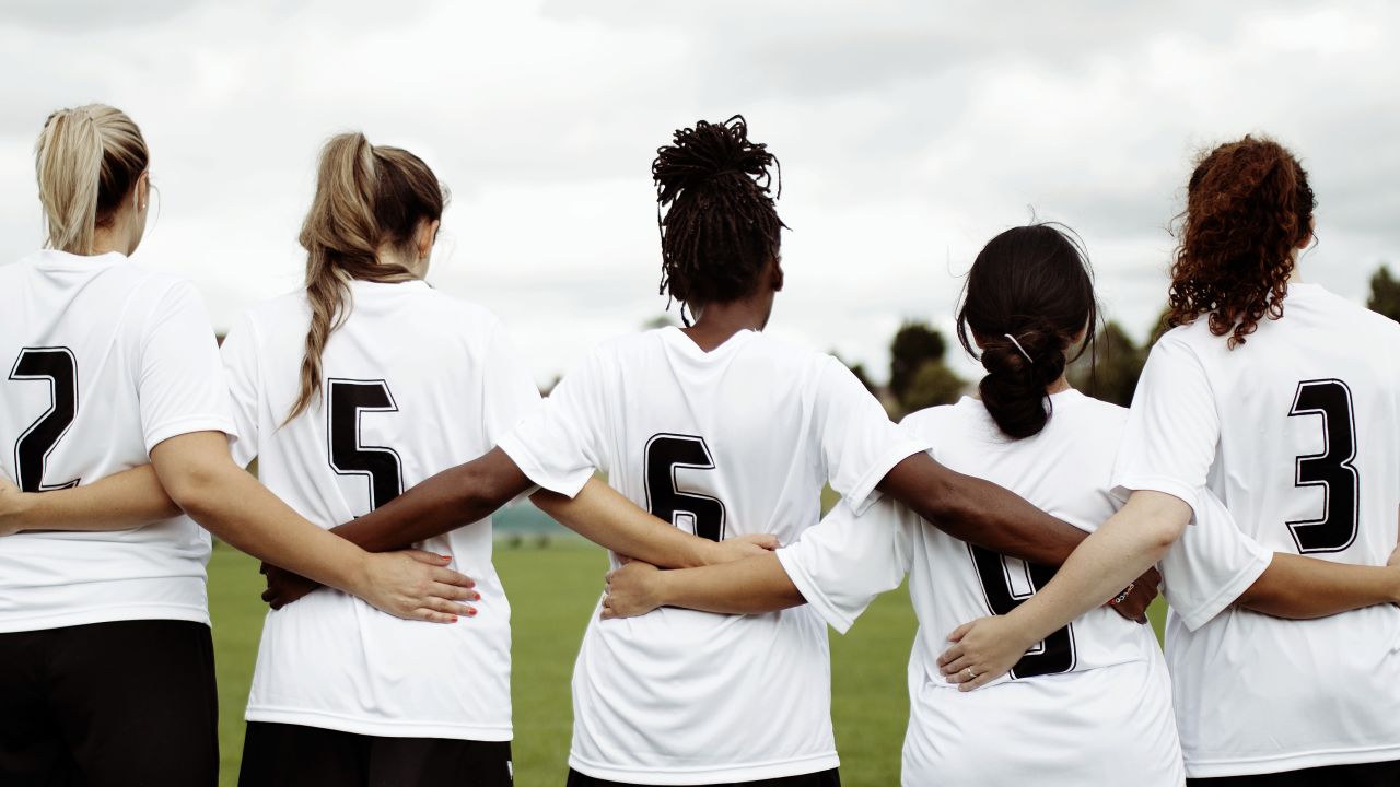 Female soccer players huddling and standing together