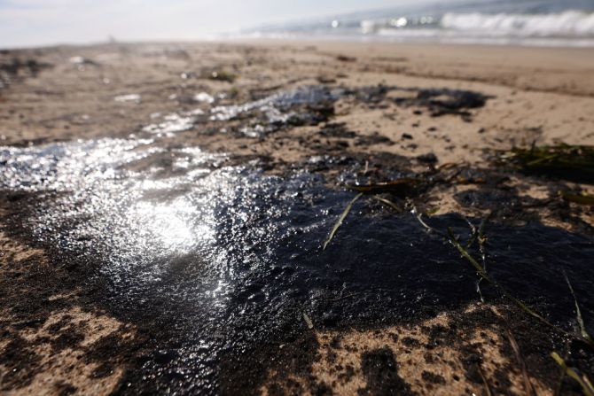 El petróleo y el agua de mar se acumulan en un charco de marea en Newport Beach, California.