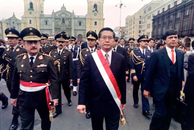 FOTOS | La vida política de Alberto Fujimori en imágenes --- Alberto Fujimori es un político peruano, de origen japonés, que presidió Perú entre 1990 y 2000. Su Gobierno estuvo lleno de controversias y acusaciones de crímenes, por las que finalmente fue condenado a 25 años de prisión. En esta foto aparece en un desfile militar en Lima en julio de 1991.  →