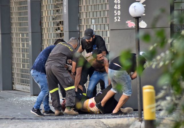 Miembros de la defensa civil libanesa y otras personas evacuan a una persona caída en medio de los enfrentamientos en Beirut.