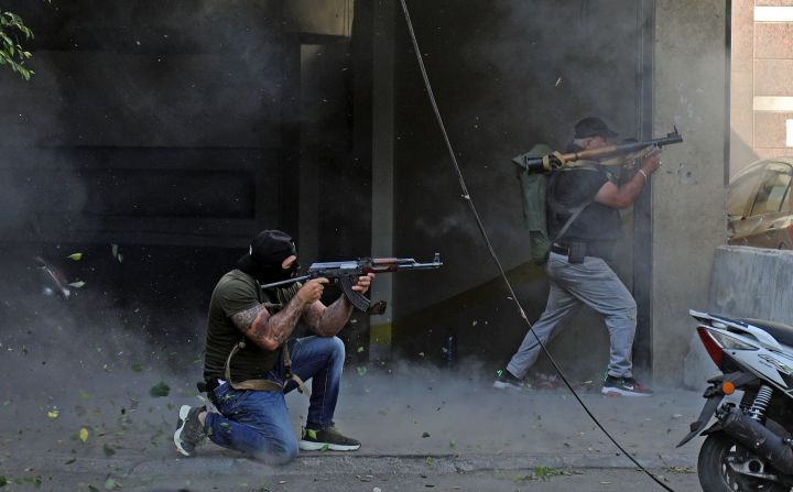 Combatientes chiites de los movimientos Hezbollah y Amal apuntan con un rifle de asalto Kalashnikov y un lanzagranadas propulsado por cohetes.