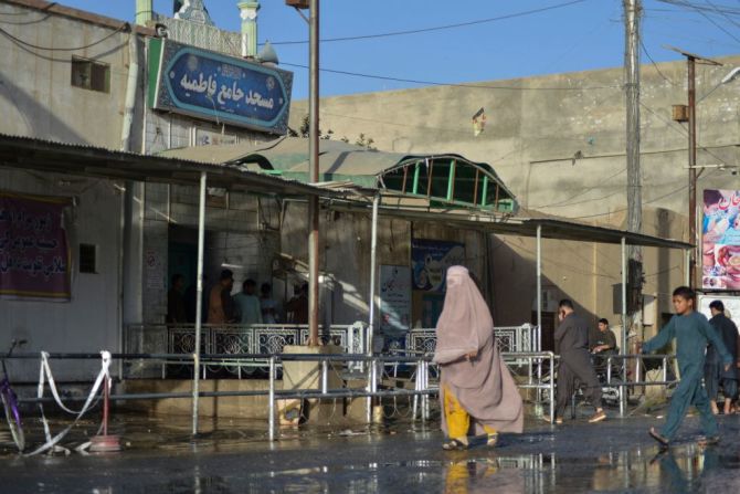 Una mujer vestida con burka pasa por delante de la entrada de la mezquita en Kandahar en la que se produjeron las trágicas explosiones.