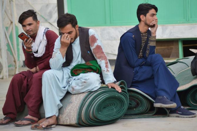 Hombres afganos sentados en un patio dentro de la mezquita chiita en Kandahar tras las explosiones.