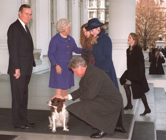 En una fotografía tomada el 20 de enero de 1993 en las escalinatas de la Casa Blanca en Washington el presidente electo Bill Clinton acaricia al perro de Bush, Millie, mientras la primera dama Barbara Bush saluda a Hillary Clinton.