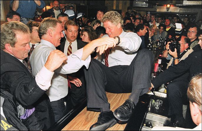 Clinton es ayudado a subir a la barra de un bar en el Eire Pub por el alcalde de Boston, Ray Flynn, durante una parada de campaña.