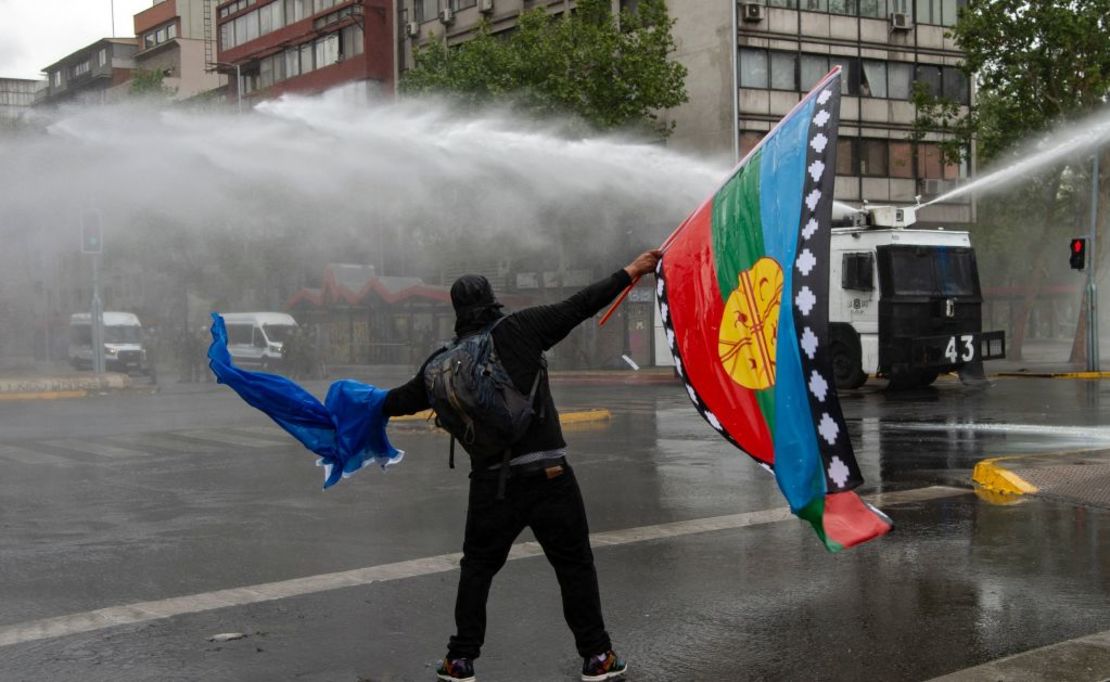 Un hombre sostiene una bandera mapuche mientras se enfrenta a la policía durante enfrentamientos en Santiago, el 10 de octubre de 2021.