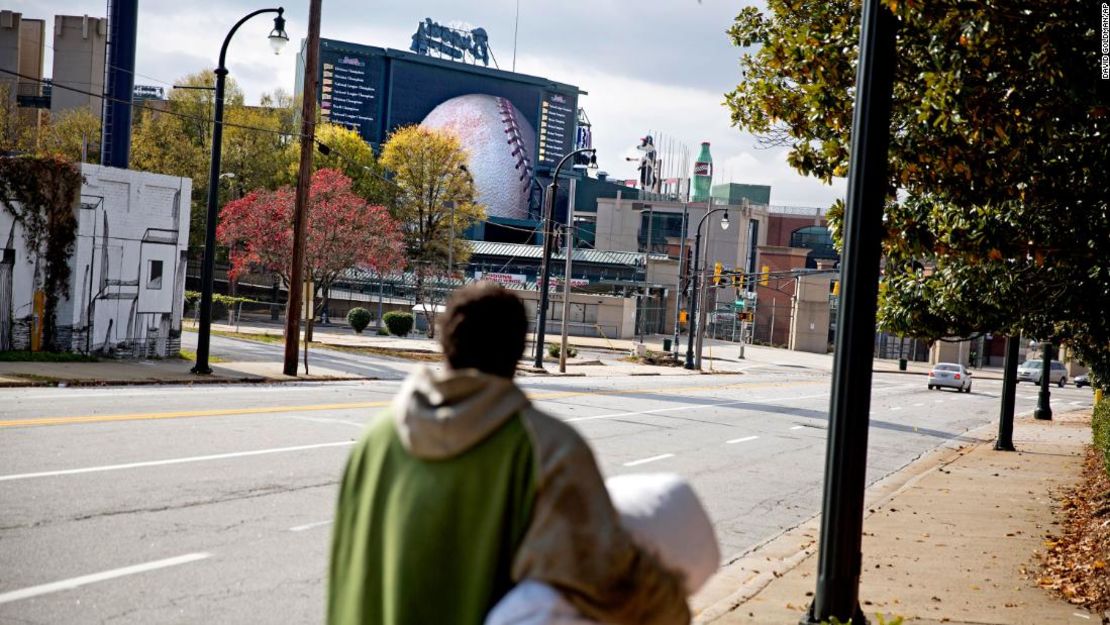 Un peatón camina por la calle mientras el Turner Field, antiguo hogar de los Bravos de Atlanta, se sitúa en el fondo. Los Bravos abandonaron el Turner Field tras la temporada 2016 para instalarse en un nuevo estadio en los suburbios del condado de Cobb.