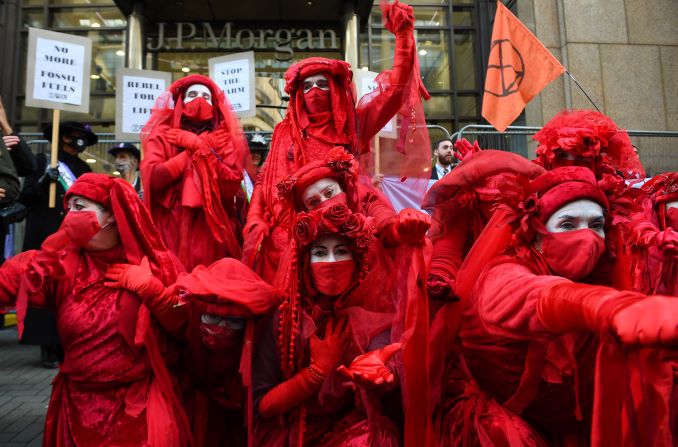 de la Brigada Rebelde Roja, una compañía internacional de artistas, se unen a los activistas del grupo Extinction Rebellion mientras se manifiestan frente a las oficinas de JP Morgan en Glasgow el 2 de noviembre de 2021.