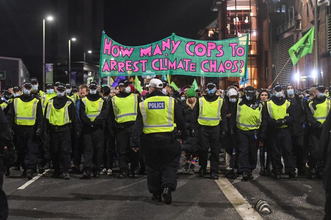 "¿Cuántos policías se necesitan para detener al caos climático?", dice esta pancarta que hace un juego de palabras con el nombre de la conferencia en inglés, la COP, que portaron integrantes del movimiento Extinction Rebellion durante una protesta en Glasgow el 3 de noviembre.