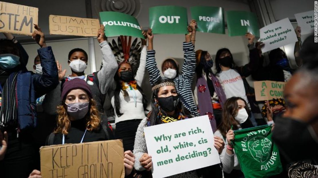 Activistas del clima protestan mientras construyen un corredor humano al inicio de la sesión de las Plenarias de Clausura, protestando "Fuera contaminadores, adentro personas" el 11 de noviembre de 2021.