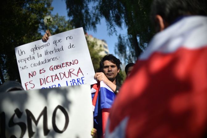 En México, un manifestante sostiene un cartel con una leyenda que acusa al gobierno de Cuba de ser una dictadura.