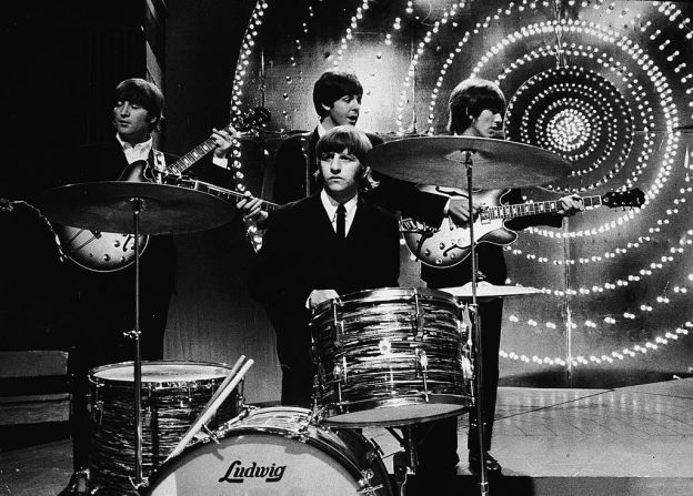 The Beatles tocan en vivo en el escenario frente a un telón de fondo iluminado en el Centro de Televisión de la BBC, en junio de 1966.