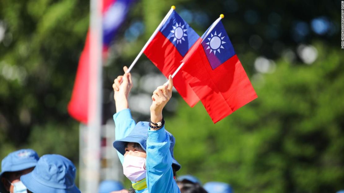 Una mujer sostiene banderas taiwanesas frente al Palacio Presidencial antes de que comience la celebración del Día Nacional en Taipei, Taiwán, el 10 de octubre de 2021.