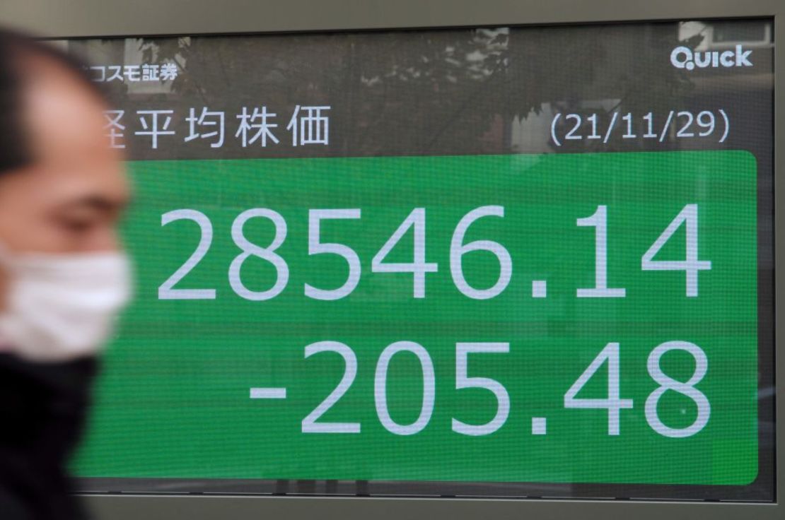 Un peatón pasa junto a un tablero de cotización electrónico que muestra los precios de las acciones de la Bolsa de Valores de Tokio en Tokio el 29 de noviembre de 2021.