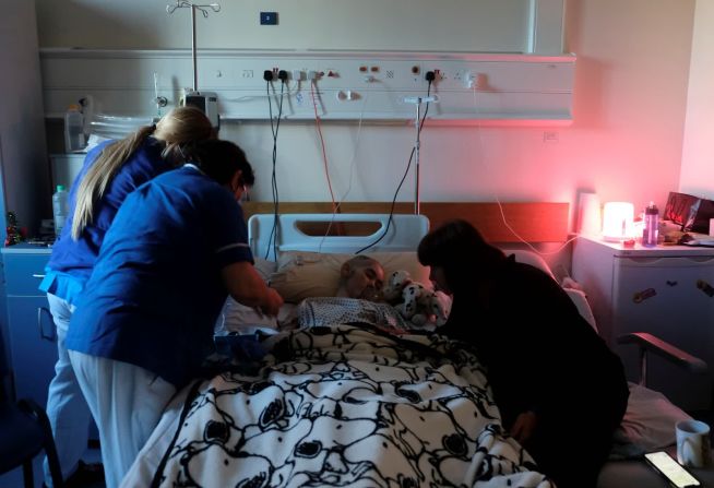 3 de enero — las enfermeras Naomi Balzan y Nanette Azzopardi istran analgésicos y sedantes a Rebecca Zammit Lupi, una paciente de cáncer de 15 años, mientras su madre, Marisa Ford, está a su lado en el Hospital Mater Dei en Msida, Malta. Esta foto fue tomada por el padre de Rebecca, el fotógrafo de Reuters Darrin Zammit Lupi. Fue la última foto que le tomó mientras aún estaba viva. Murió aproximadamente una hora después.