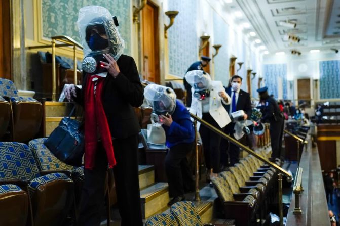 6 de enero — las personas se ponen capuchas de emergencia mientras se refugian en la Cámara. A los legisladores, asistentes y periodistas se les pidió que se pusieran las capuchas después de que se lanzara gas lacrimógeno en el Capitolio.