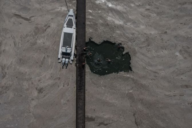 11 de junio — en esta foto aérea, unos niños nadan en un embarcadero rodeado de mucílago marino, también conocido como "moco de mar", en Kocaeli, Turquía. El litoral del mar de Mármara, en Turquía, se ha cubierto de esta gruesa capa de mucílago, que amenaza la vida submarina. El mucílago está compuesto principalmente por bacterias y secreciones mucosas del fitoplancton. La contaminación provoca un exceso de nutrientes en el agua que actúa como catalizador de estas floraciones masivas, al igual que la crisis climática provocada por el ser humano.