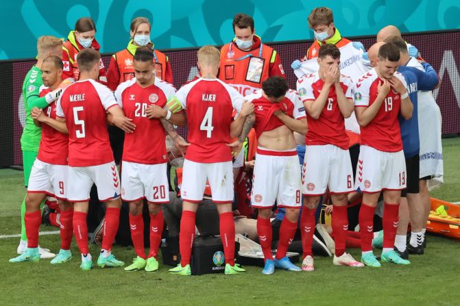 12 de junio — jugadores de fútbol de Dinamarca rodean con sus brazos a su compañero Christian Eriksen mientras los paramédicos trabajan para reanimarlo durante un partido de la Eurocopa 2020. Eriksen se desplomó en medio del partido y tuvo que ser reanimado con R y un desfibrilador.