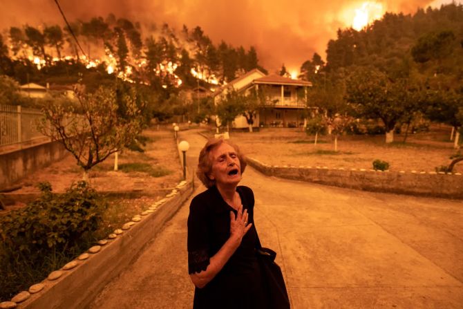 8 de agosto — una mujer reacciona mientras un incendio forestal se acerca a su casa en el pueblo de Gouves, en la isla de Evia, Grecia. Miles de residentes se vieron obligados a huir de Evia, que está a unos 160 kilómetros al norte de Atenas.