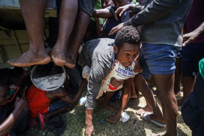 20 de agosto — un hombre se arrastra con una bolsa de arroz donada después de que la gente en Vye Terre, Haití, se tomara un camión cargado de suministros de ayuda. Haití fue devastada seis días antes por un terremoto de magnitud 7,2.