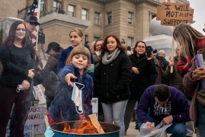 6 de marzo — un niño lanza una mascarilla quirúrgica al fuego durante un acto de quema de mascarillas en la sede del Estado de Idaho en Boise. La gente se reunió en al menos 20 ciudades de todo el estado para protestar por las restricciones de covid-19.