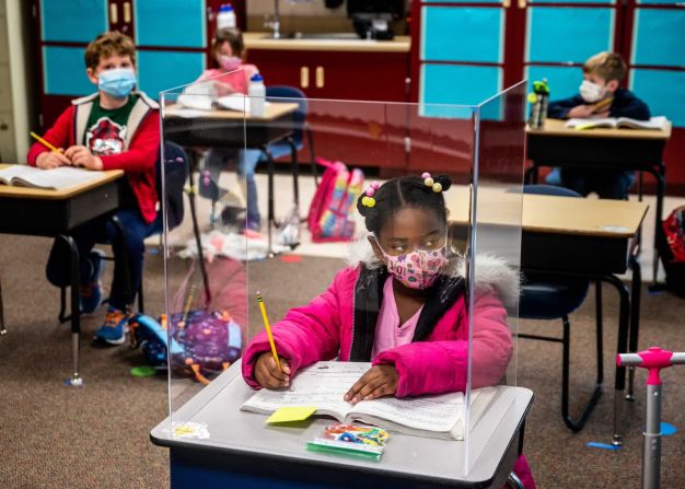 8 de marzo — la alumna de primer grado Sophia Frazier hace sus tareas escolares detrás de un separador de plástico en la escuela primaria Two Rivers de Sacramento, California. Los separadores estaban delante de los pupitres más cercanos a la mesa del profesor. Los alumnos de primer grado volvieron a clase una semana antes. Era el primer día para los estudiantes de los grados tercero al quinto.