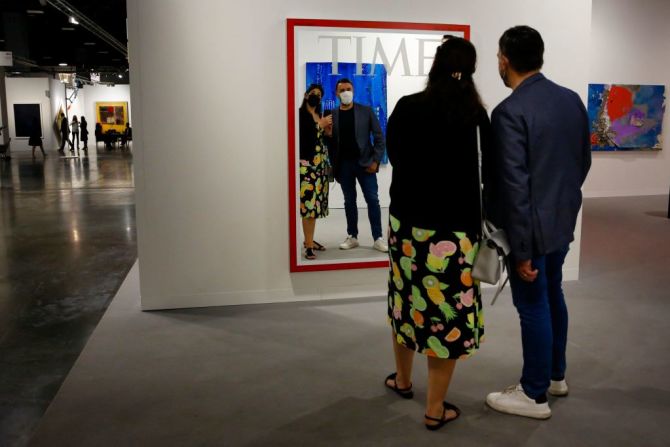 Dos personas interactúan con una obra de arte, que simula la portada de la Revista Time.