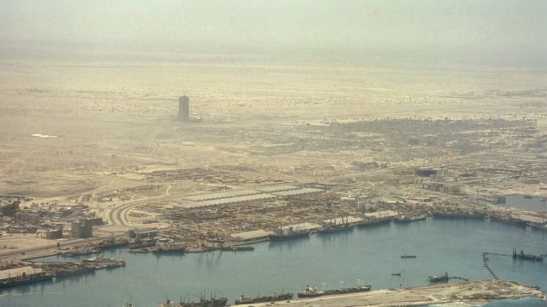 "Off Centre / On Stage" es una exposición de fotografías de la ciudad tomadas entre 1976 y 1979 por los arquitectos británicos Stephen Finch y Mark Harris. La exposición muestra a Dubái en el momento en que empezaba a ser reimaginada como una ciudad de arquitectura imponente. Esta vista desde arriba sobre Port Rashid de 1977 muestra el World Trade Centre, el primer rascacielos de Dubái, que en ese momento estaba en construcción. Cortesía de Mark Harris, Biblioteca John R. Harris