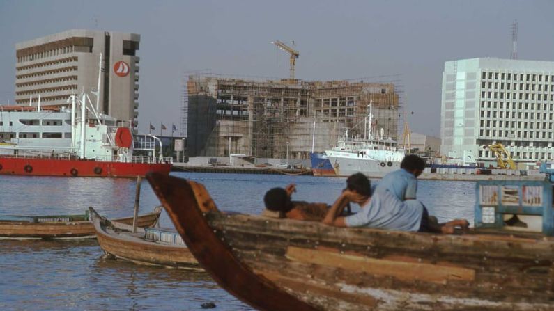 Los hombres de esta imagen de 1977 de Dubai Creek miran hacia el edificio del Ayuntamiento, que está en construcción. "Probablemente están en Dubái por un día, una semana, tal vez no tienen idea de cuánto tiempo se quedan", dijo Reisz. "Pero su vida está en ese barco, que capta el tipo de movilidad de la gente, la transitoriedad de la vida en Dubái. Te imaginas que quizá sea su segunda o tercera vez en Dubái y que han visto cómo el edificio del Ayuntamiento de Dubái se hace más grande cada vez que llegan a la orilla". Cortesía de la Biblioteca John R.Harris