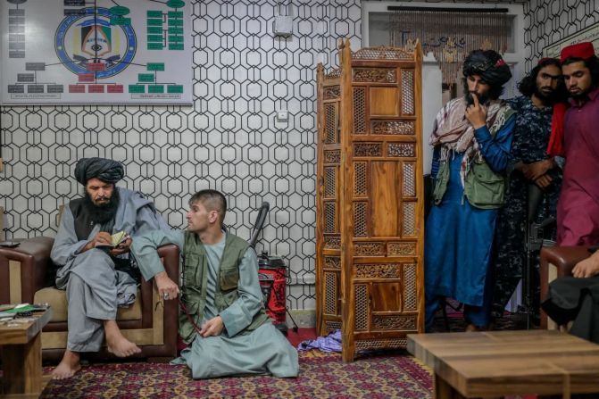 30 de septiembre — un hombre acusado de robo se sienta junto a miembros del Talibán mientras está detenido en una comisaría de policía en Kabul, Afganistán.