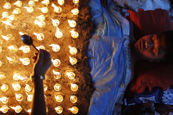 15 de octubre — un hombre yace quieto mientras los devotos encienden lámparas de aceite sobre su cuerpo como parte de los rituales para celebrar el último día del festival Dashain en Bhaktapur, Nepal.