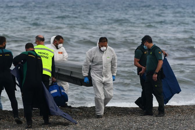 Funerarios llevan el cuerpo de un migrante en la playa del enclave español de Ceuta en mayo de 2021. Los migrantes nadaron alrededor de rompeolas rocosos que se adentran en el Mediterráneo y que marcan la frontera entre España y África.