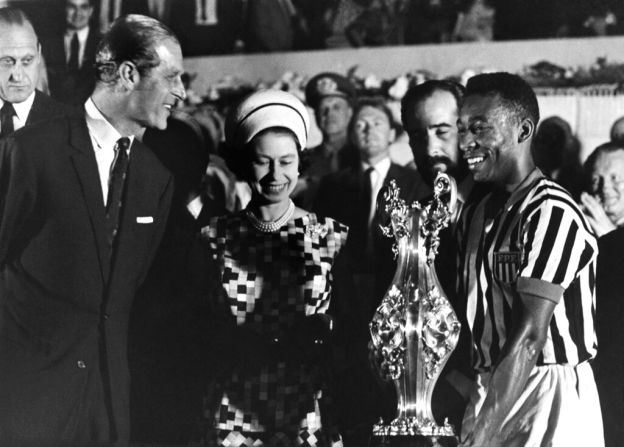 La reina Isabel II, en una gira por Sudamérica, sonríe después de darle una copa a Pelé en Río de Janeiro, Brasil, el 10 de noviembre de 1968. A la izquierda está el príncipe Felipe. Crédito: AP