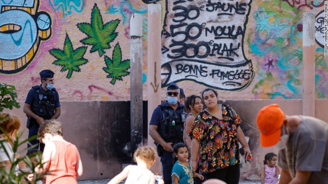 Habitantes de la zona y agentes de policía frente a un muro en Marsella que muestra los precios de las drogas durante una visita del presidente Macron el 1 de septiembre de 2021.