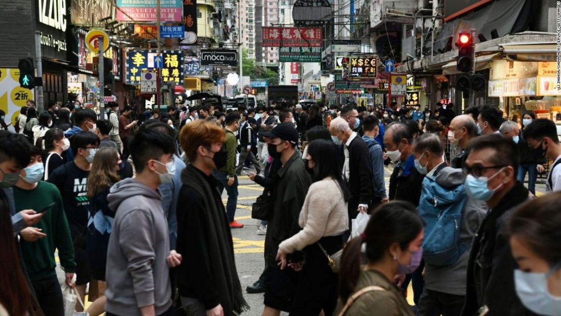 Personas que usan máscaras cruzan una calle en el distrito densamente poblado de Mong Kok en Hong Kong el 22 de diciembre de 2021.