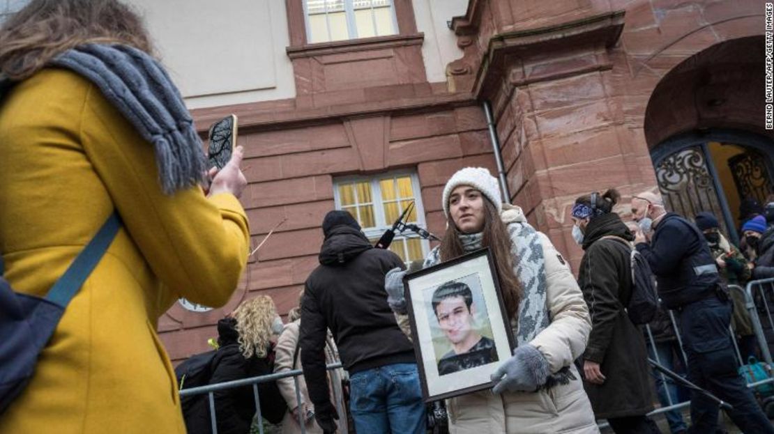 La activista siria Samaa Mahmoud muestra una foto de su tío, Hayan Mahmoud, mientras ella y otras personas esperan afuera del juzgado en Koblenz, Alemania occidental, este jueves.