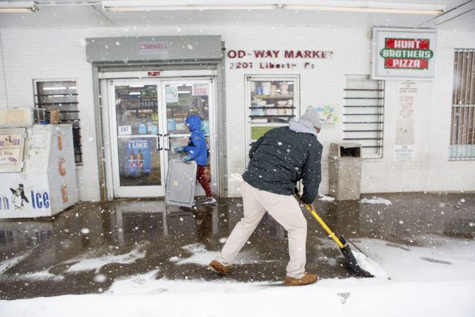 Un hombre limpia la acera para los clientes fuera del Food Way Market en Roanoke, Virginia, el 16 de enero.