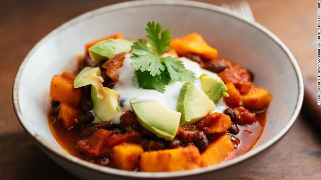 Este chili vegano, hecho con camotes y frijoles negros, está cubierto con yogur de soya y aguacate.