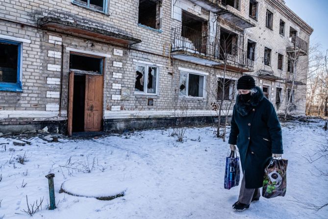 Una mujer pasa junto a un edificio de apartamentos dañado en Marinka el 22 de enero. "El estado de ánimo era sombrío, deprimido y resignado", dijo Fadek. "La gente sigue los movimientos de su vida diaria".