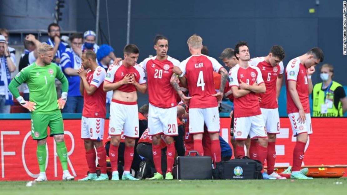 Los jugadores de Dinamarca se ven abatidos mientras su compañero de equipo Christian Eriksen (oculto) recibe tratamiento médico durante su partido de la Eurocopa 2020 contra Finlandia.