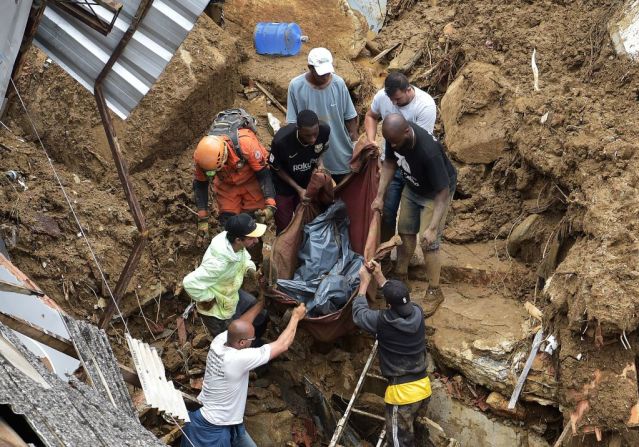 Personas sacan el cadáver de una víctima de entre los escombros después de un deslizamiento de tierra en Petrópolis, Brasil, el 16 de febrero de 2022.