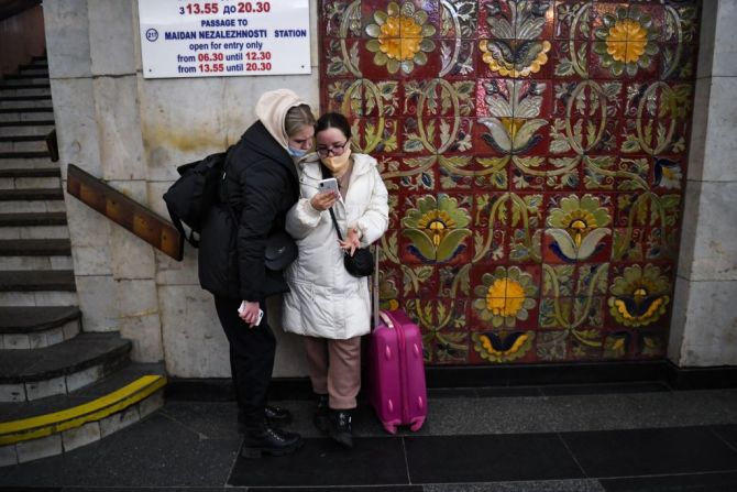 Dos mujeres jóvenes con una maleta usan un teléfono en una estación de metro en Kyiv a primera hora del 24 de febrero de 2022.