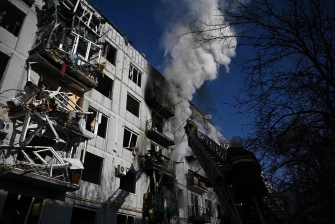 Bomberos trabajan en un incendio en un edificio después de los bombardeos en la ciudad de Chuguiv, en el este de Ucrania, el 24 de febrero de 2022, mientras las fuerzas armadas rusas intentan invadir Ucrania desde varias direcciones, utilizando sistemas de cohetes y helicópteros para atacar la posición ucraniana en el sur. dijo el servicio de guardia de fronteras.