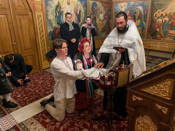 Sviatoslav Fursin, a la izquierda, y Yarina Arieva, al centro, se arrodillan durante la ceremonia de su boda en la catedral de San Miguel en Kiev el 24 de febrero. Arieva, una diputada de 21 años del ayuntamiento de Kiev, y Fursin, un ingeniero de software de 24 años, habían planeado casarse en mayo, pero lo cambiaron debido a los ataques de las fuerzas rusas este jueves.