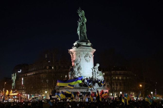 Manifestantes ondean banderas ucranianas y se reúnen alrededor del Monumento a la República mientras asisten a una protesta convocada por la Unión de Ucranianos en Francia (Union des Ukrainiens de France) y otras asociaciones en la plaza de la República en París el 24 de febrero de 2022.