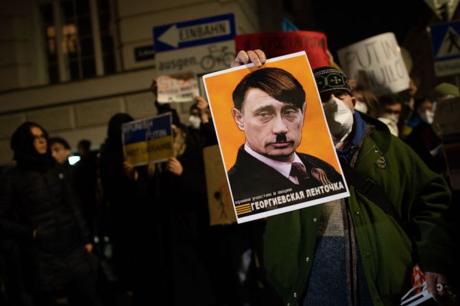 Un manifestante sostiene un cartel con una ilustración que muestra al presidente ruso, Vladimir Putin, como Adolf Hitler durante una protesta frente a la embajada rusa el 24 de febrero de 2022 en Viena, Austria.