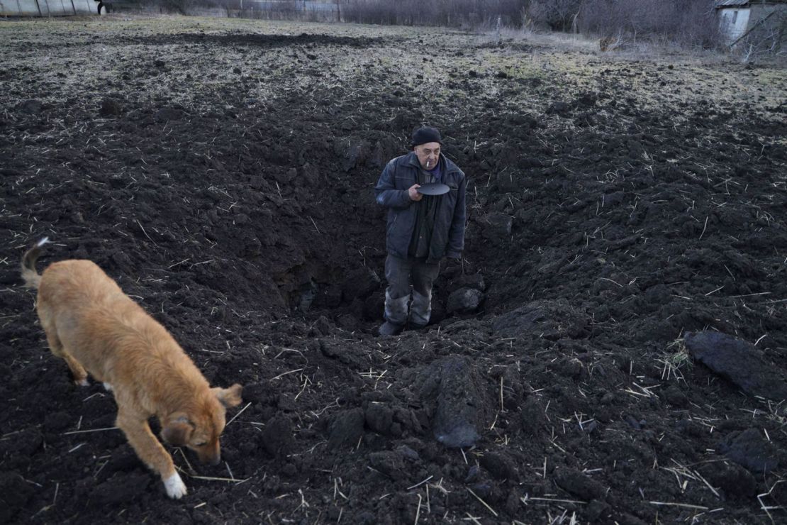 Un residente local muestra la profundidad de un cráter de un bombardeo en un campo detrás de su casa en el pueblo de Tamarchuk, Ucrania, el domingo 20 de febrero.
